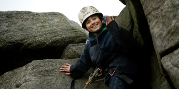 Child waving while rock climbing